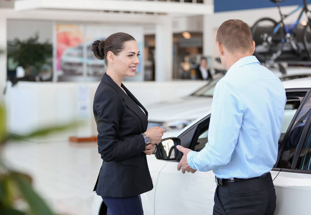 Young saleswoman working with client in car dealership - Fotoğraf, Görsel