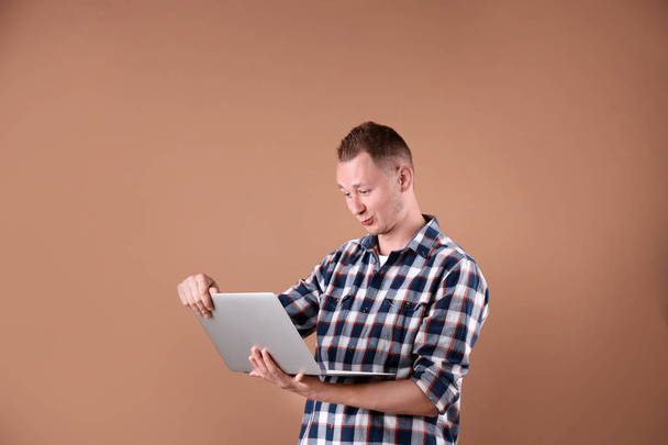 Portrait of handsome man with laptop on color background - Fotografie, Obrázek