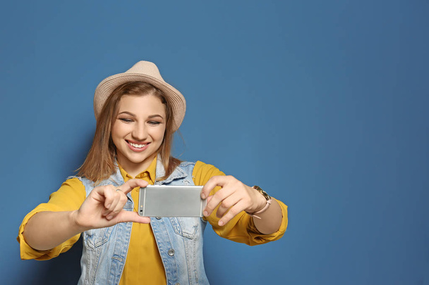 Attractive young woman taking selfie on color background - Foto, Imagen