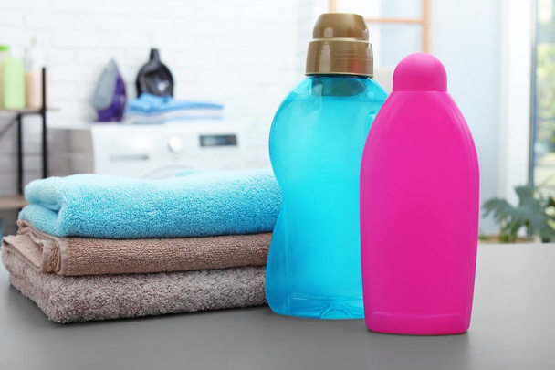 Stack of clean towels and bottles with detergents on table in bathroom - Foto, Imagem
