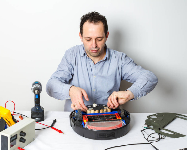 Repairman changing batteries on robotic vacuum cleaner. Repairing robot cleaner - Foto, imagen
