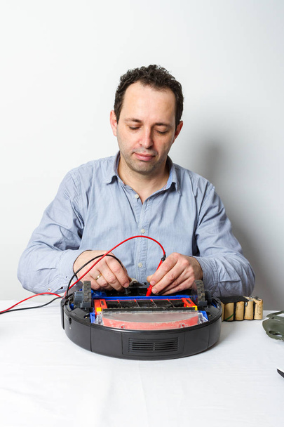 Man changing batteries on robotic vacuum cleaner. Repairing robot cleaner - Φωτογραφία, εικόνα
