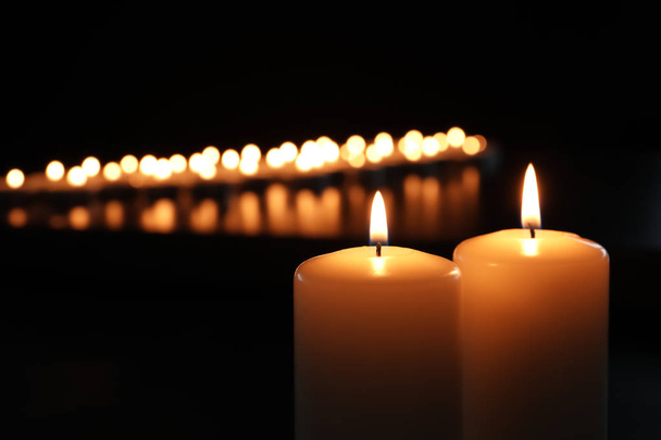 Small wax candles burning in darkness, closeup - Foto, afbeelding