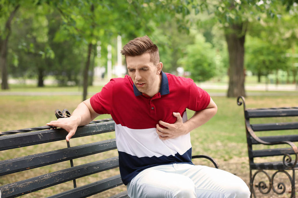 Mladý muž s bolesti na hrudi v parku. Srdeční infarkt - Fotografie, Obrázek