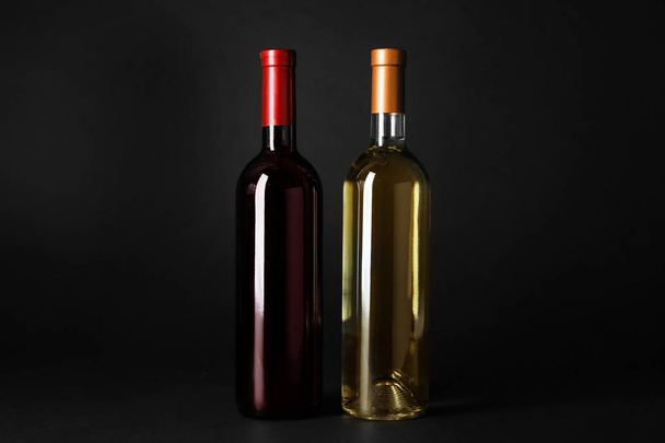 暗い背景に高価な赤と白ワインのボトル - 写真・画像