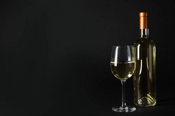 Bottiglia e bicchiere di costoso vino bianco su sfondo scuro
 - Foto, immagini
