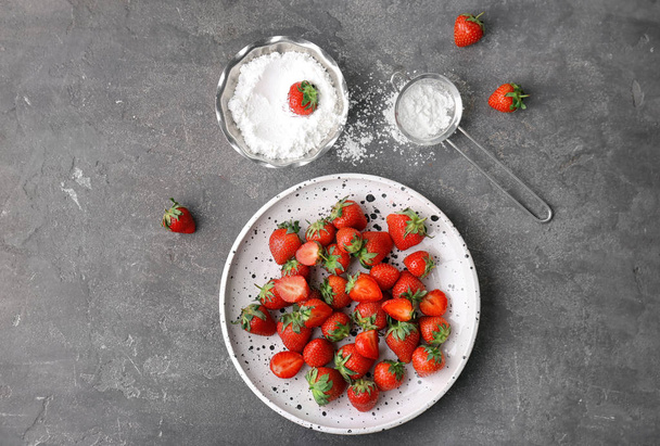 Flat lay composition with ripe red strawberries and sugar powder on grey background - Foto, afbeelding