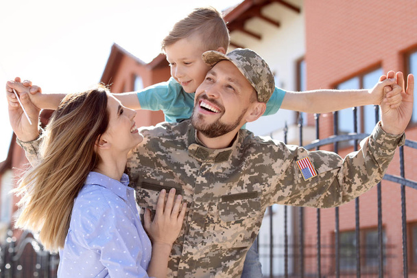 Male soldier reunited with his family outdoors. Military service - 写真・画像