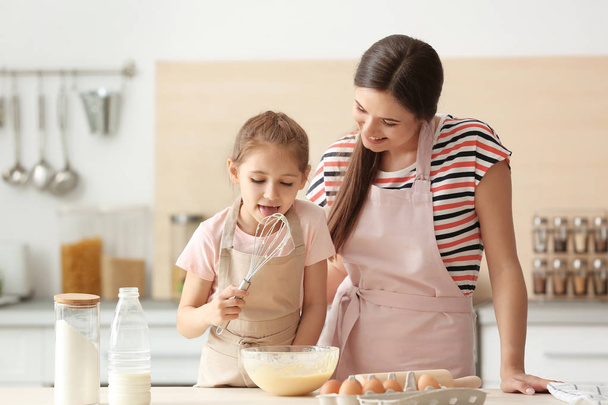 Mother and her daughter making dough at table in kitchen - Foto, Imagen