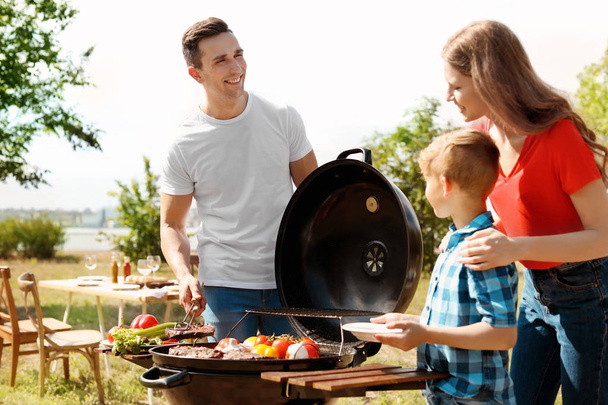 Happy family having barbecue with modern grill outdoors - Fotó, kép