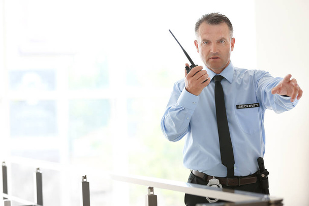 Protetor de segurança masculino usando transmissor de rádio portátil dentro de casa
 - Foto, Imagem