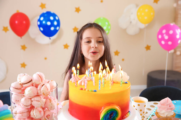 Cute little girl blowing out candles on her birthday cake indoors - Foto, Imagem