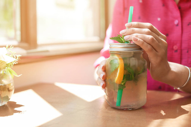 Young woman with mason jar of tasty natural lemonade in cafe, closeup. Detox drink - Foto, Bild