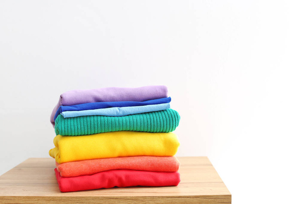 Stack of rainbow clothes on table against white background - Fotoğraf, Görsel