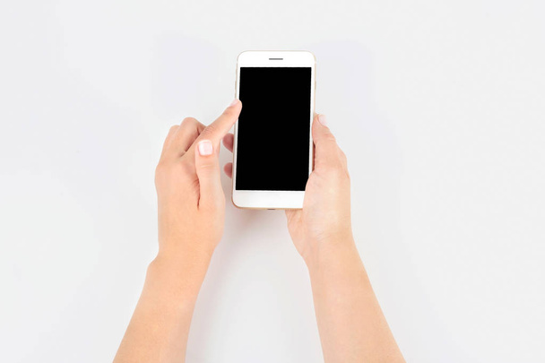 Young woman holding mobile phone with blank screen in hand on white background - Fotó, kép