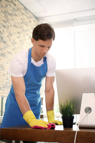 Young man in apron and gloves cleaning office - Photo, Image
