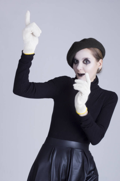 Young woman mime in gloves on a gray background - Foto, Bild