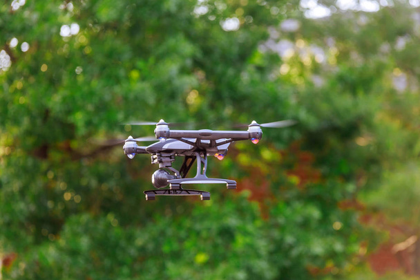 Drone with professional cinema camera flying over a summer park. - Photo, Image