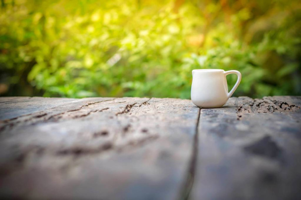 Маленький білий глечик на дерев'яному столі вранці
 - Фото, зображення