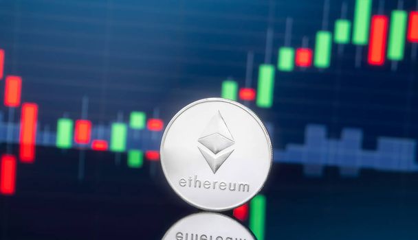 Ethereum (ETH) and cryptocurrency investing concept - Physical metal ethereum coins with global trading exchange market price chart in the background. - Photo, Image