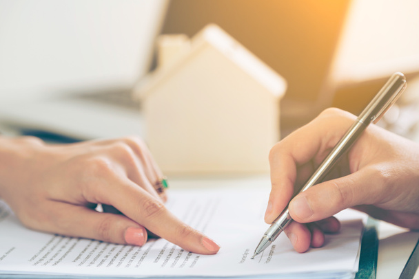 Klient unterschreibt Dokument über Immobilienaktivitäten. Anwalt oder Immobilienmakler zeigen auf den Signaturpunkt. Geschäftskonzept des Verkaufs und Kaufs von Häusern. - Foto, Bild