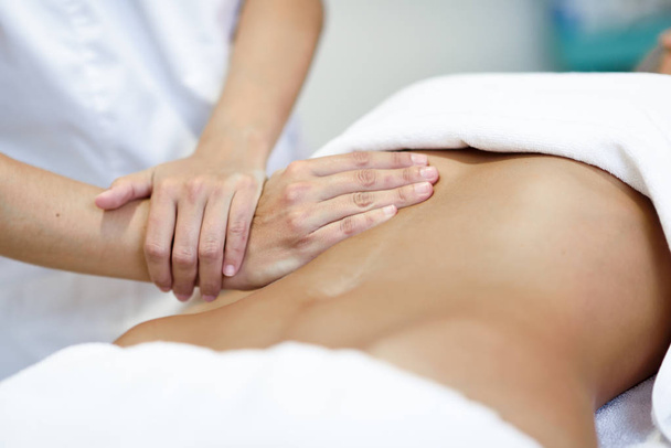 Handen masseren van de vrouwelijke buik. Therapeut druk uit te oefenen op de buik. Vrouw ontvangen van massage in de spa salon - Foto, afbeelding