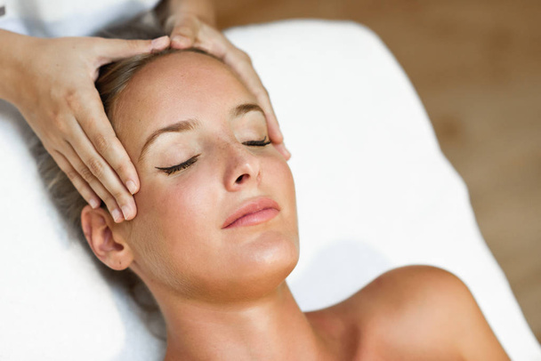 Mladá blond žena přijímá masáž hlavy ve wellness centru se zavřenýma očima. Žena pacient dostává léčbu profesionální terapeut. - Fotografie, Obrázek