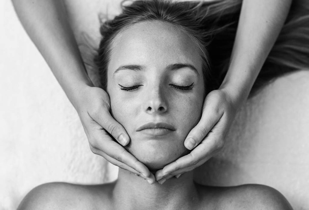 Giovane donna bionda che riceve un massaggio alla testa in un centro benessere con gli occhi chiusi. Paziente di sesso femminile è in trattamento da terapeuta professionista
. - Foto, immagini