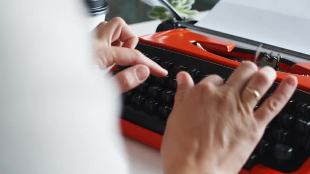 Женщина вручную печатает на красной винтажной пишущей машинке
 - Кадры, видео