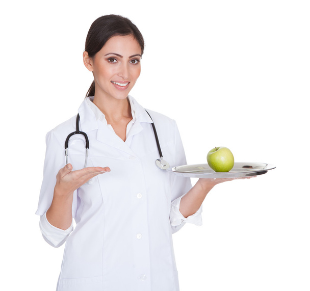 Young Female Doctor Presenting Green Apple - Foto, Imagen