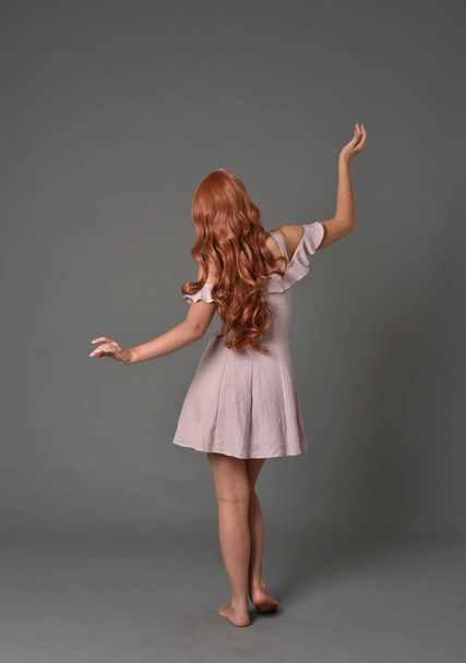 po celé délce portrét dívka, která nosí růžové letní šaty. představovat stojící na šedé studio pozadí - Fotografie, Obrázek