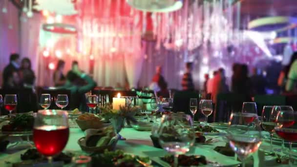 Mesa de banquete en un restaurante con vasos y una vela. La gente baila en el fondo de la mesa. Mesa de banquete, gente bailando en el fondo
 - Imágenes, Vídeo