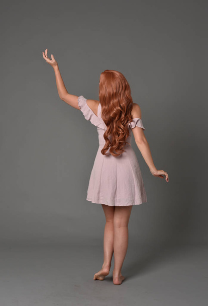 retrato de comprimento total da menina vestindo vestido de verão rosa. em pé pose no fundo do estúdio cinza
 - Foto, Imagem