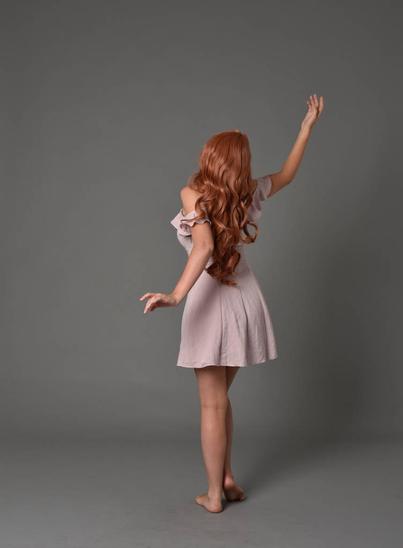 retrato de longitud completa de la niña con vestido de verano de color rosa. pose de pie sobre fondo gris estudio
 - Foto, Imagen