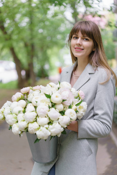 Beautiful bouquet of white peonies in woomans hands . Floral composition, daylight. Wallpaper. Vertical photo - Foto, imagen