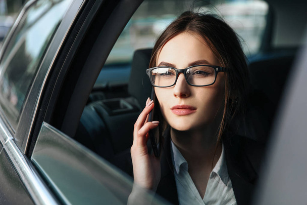 Business woman solves important questions by phone in the car - Foto, immagini