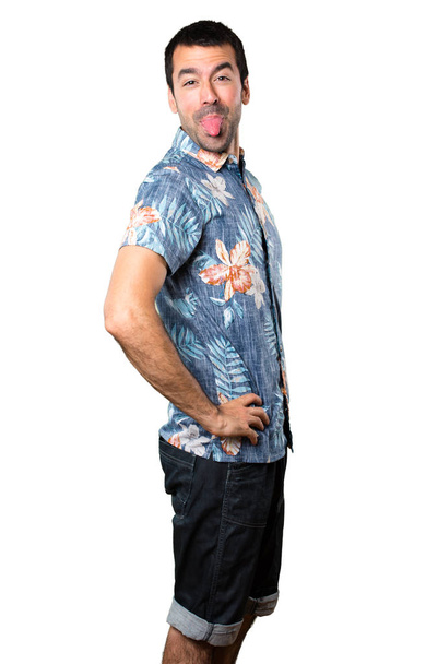 Knappe man met bloem shirt maken van een grap op geïsoleerde witte achtergrond - Foto, afbeelding