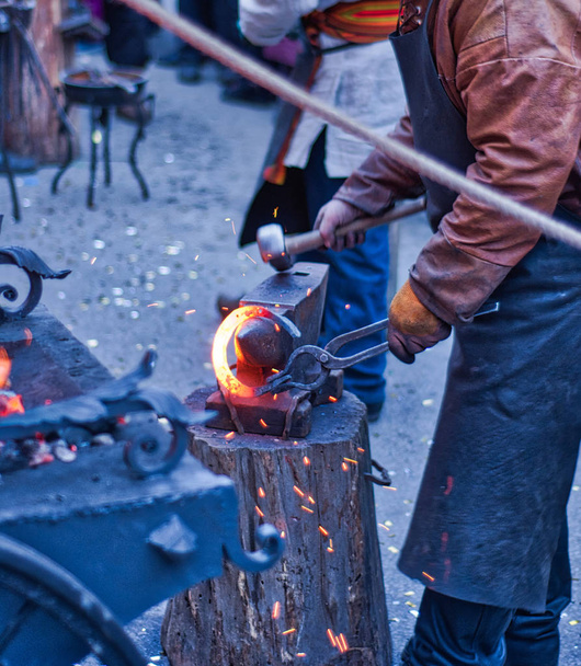 Le forgeron travaille sur la fer à cheval sur un petit four à forge. Forgeage de fer à cheval à la foire russe de Moscou
. - Photo, image