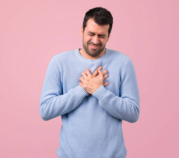 Homme avec un pull bleu ayant une douleur dans le cœur. Crise cardiaque sur fond rose
 - Photo, image