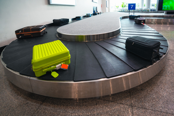 A bőröndöt vagy bőröndöt a szállítószalagon keresztül szállítják a repülőtéri terminál érkezési várójába. - Fotó, kép