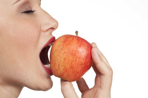 women biting into fresh apple closeup on white background - Photo, Image