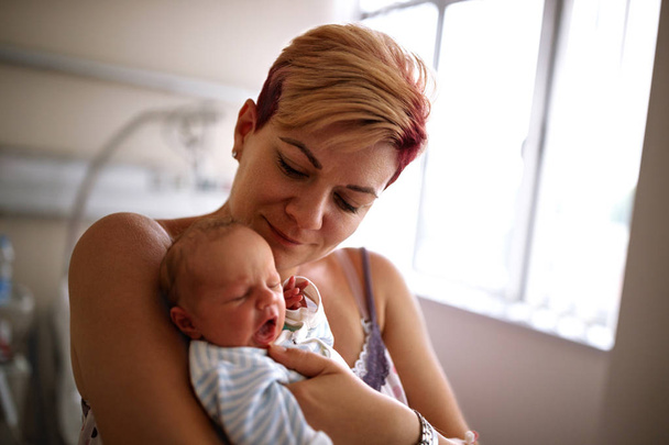 Mother holding her newborn baby in maternity clinic - Φωτογραφία, εικόνα