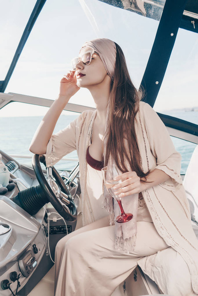 a luxurious young girl enjoys a rich life on her white yacht, drinks champagne and sails on the Caribbean sea - Photo, Image