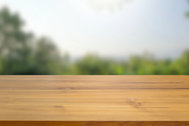 Empty wood table top against blur green leaves and blur sky bokeh background. used for display or montage your products advertisement. nature tone - Photo, Image