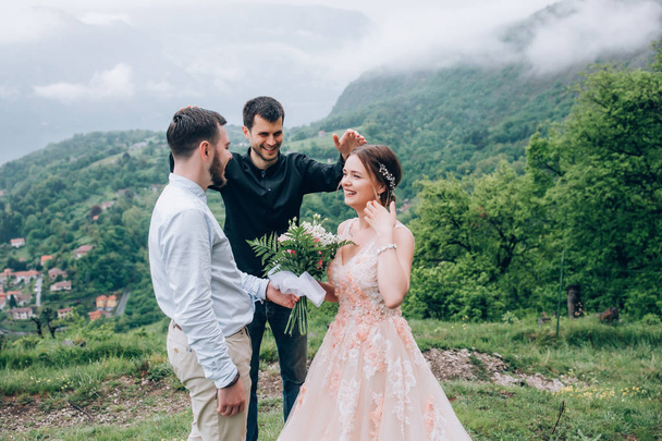 Walking newlyweds in nature. Groom and bride against the background of mountains and the sea. The priest blesses the young. - Fotó, kép