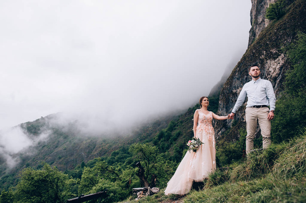 Walking newlyweds in nature. Groom and bride against the background of mountains and the sea. - Valokuva, kuva