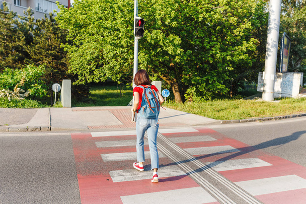Женщина нарушает правила дорожного движения и бежит через дорогу на красный светофор.
 - Фото, изображение