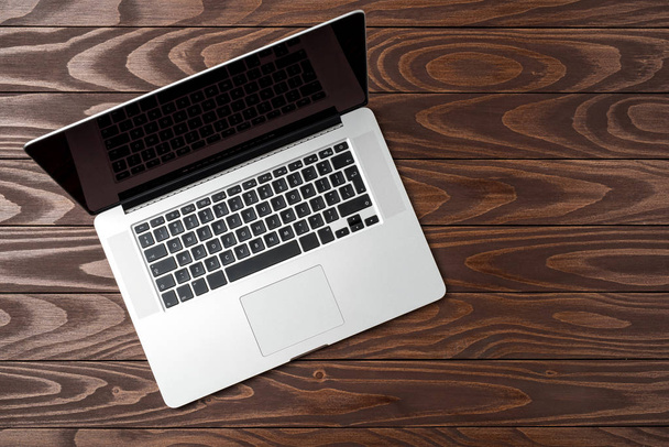 Laptop on dark wooden background. Top view - Fotografie, Obrázek