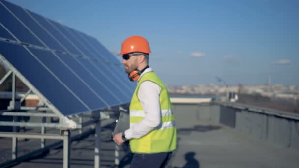 Solar battery expert is turning around and walking towards the camera - Filmagem, Vídeo