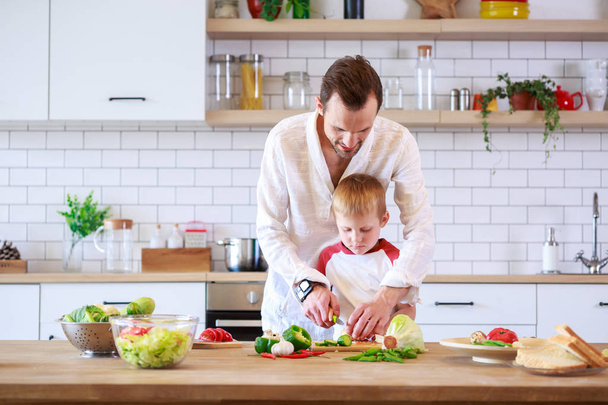 Picture of young father and son cooking at table with vegetables - Fotografie, Obrázek